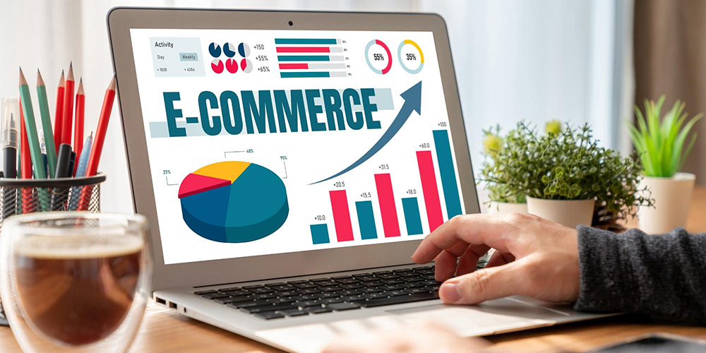 Laptop mit ansteigendem Balkendiagramm und Schrift "E-Commerce" auf dem Screen