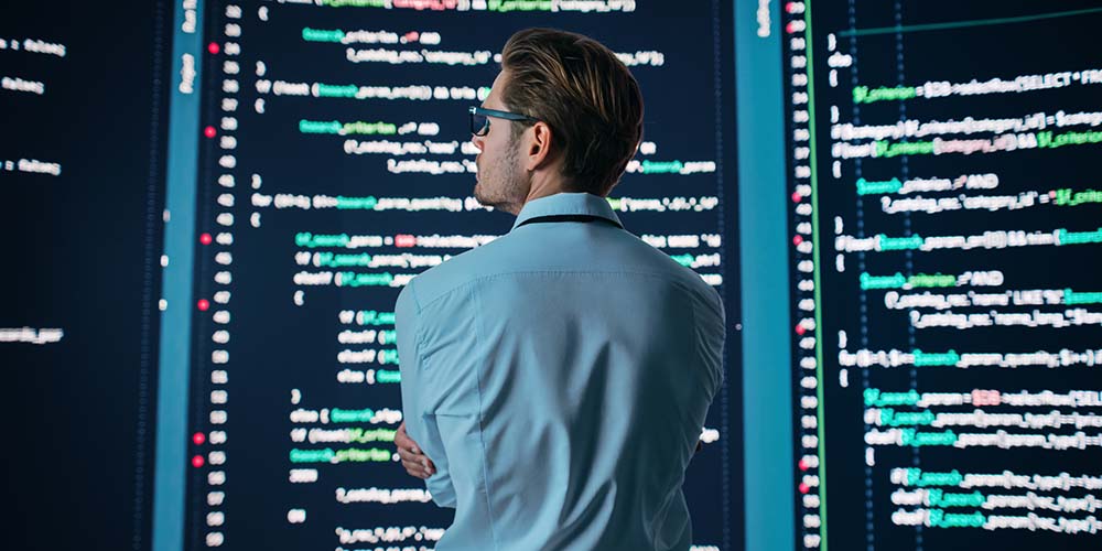 Entwickler blickt auf große Screens mit Code