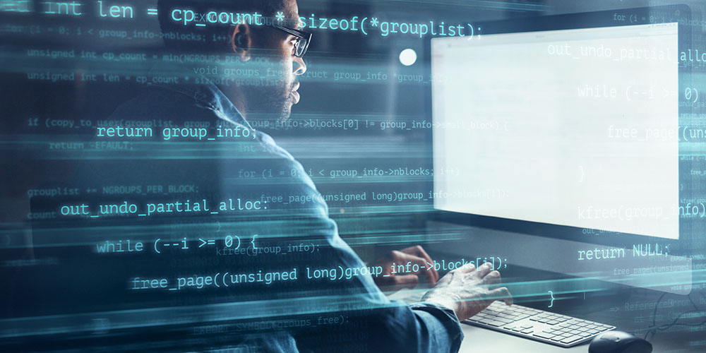 Mann vor einem PC-Bildschirm mit Code
